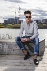 Obraz premium Handsome young man wearing jeans, sweater and sunglasses