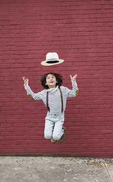 A happy mixed race boy tries to catch hat on his head