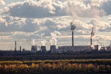 the pipes of a large plant smoke in the sky