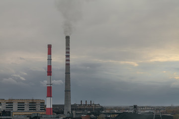 the pipes of a large plant smoke in the sky