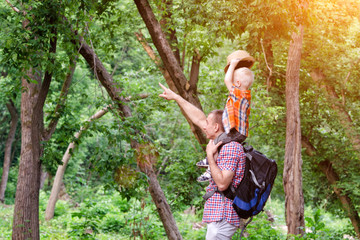 Father and son on shoulders in the forest. Summer. Side view