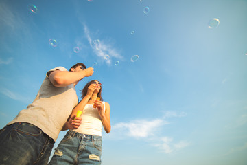 The couple blow bubbles on the background of the blue sky