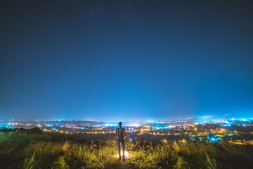 The man stand near the bonfire on the background of the city lights. night time