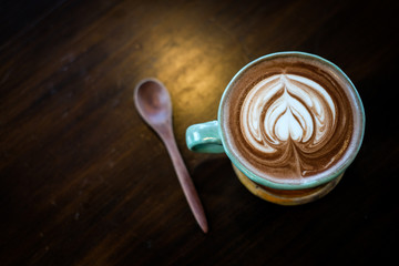 A cup of hot cocoa decorated with heart milk forth on the surface placed on a wooden tray and wooden spoon, for beverage/drink background or texture healthy diet concept.