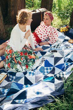 Picnic - Two Pretty Blondes Talking on Patchwork Quilt in Sunny Meadow