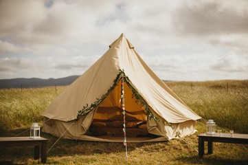 Fun floral and bunting covered canvas yurt tent in open field in California for wedding
