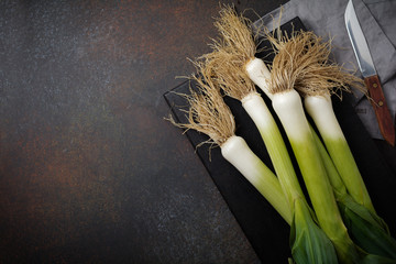 Group of leek in a vintage box on a dark concrete background. Selective focus.Top view. Copy space.