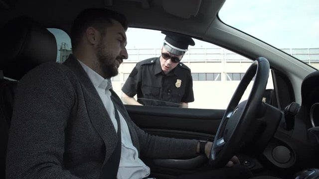 Policeman stopping a driver in a car to question him through the window on a traffic offence