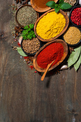assortment of spices and herbs on a wooden table, top view vertical