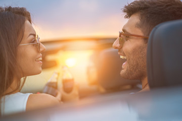 The happy couple sit with friends in a cabrio on the bright sun background