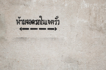 " Do not parking this area " in Thai Language and arrow show area paint on concrete wall 2
