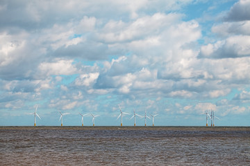 Renewable energy on the horizon. Offshore wind farm with beautiful cloudy sky.