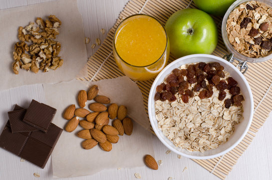 Healthy food. Fruit, homemade granola, nuts, chocolate, oatmeal, orange juice on a white table