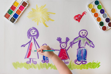 The child's hand paints a happy family
