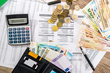 paperworks, euro bills, pen and calculator with credit card in wallt