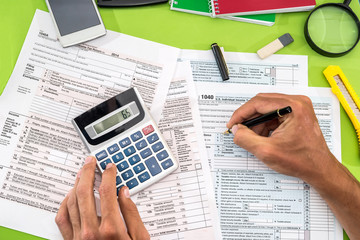 Obraz premium mężczyzna wypełniający formularz podatkowy długopisem, kalkulatorem