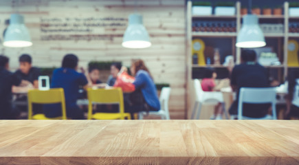 Wood table top with blur of people in community cafe shop background.For montage product display or...
