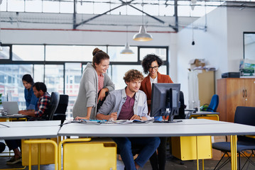 Colleagues working on a creative project in a startup office using computer