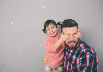 Cute little daughter and her handsome young dad are playing together in child's room. Daddy and child spend time together while sitting on the floor in bedroom