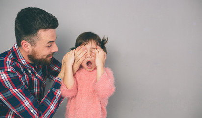 Cute little daughter and her handsome young dad are playing together in child's room. Daddy and child spend time together while sitting on the floor in bedroom