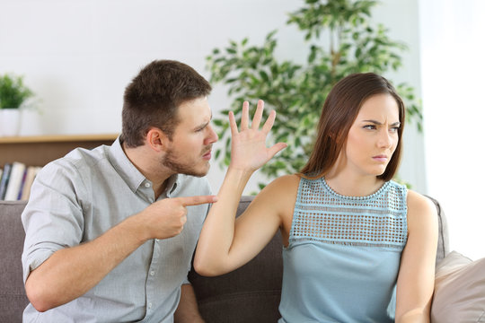 Angry couple fighting on a couch at home
