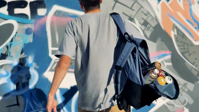A graffiti artist adds white paint on the wall. 