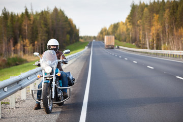 Obraz premium Kobieta na motocyklu odpoczywa na poboczu drogi krajowej z pustej drogi