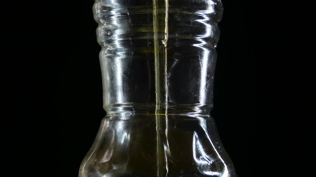 Pour the vegetable oil in the bottle, the black background.