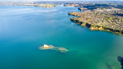 Aerial view on residential suburbs surrounded by sunny ocean harbour. Whangaparoa peninsula, Auckland, New Zealand.