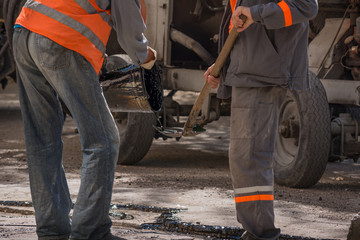 Road repair. Work details, workers pour resin road surface to cover the asphalt.