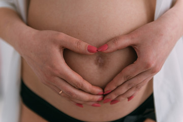 heart of the hand on the belly of a pregnant woman