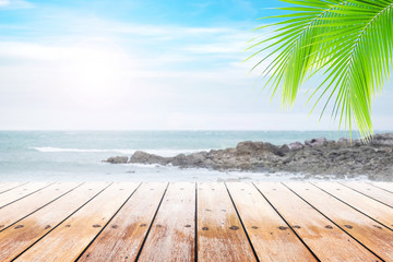 Fototapeta premium Empty wooden table and coconut leaves with party on beach blurred background in summer time.