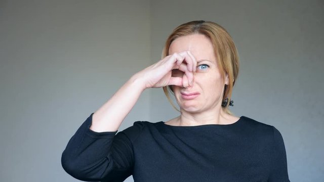 4k. Close up of beautiful blonde woman with bright blue eyes. portrait of a young woman. body language and gestures. she is disgusted and closes her nose. smell