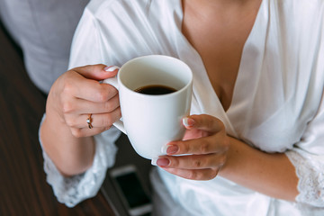  a cup of coffee in the hands of a bride in a white coat