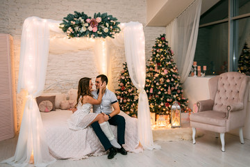  happy woman and man on a background of New Year's Christmas decor smiling in bed
