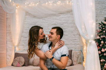  happy woman and man on a background of New Year's Christmas decor smiling in bed