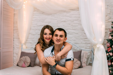  happy woman and man on a background of New Year's Christmas decor smiling in bed