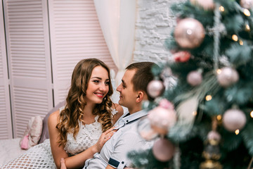  happy woman and man on a background of New Year's Christmas decor smiling in bed