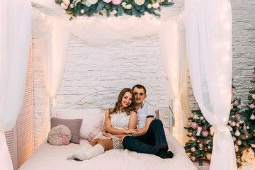  happy woman and man on a background of New Year's Christmas decor smiling in bed