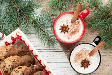 eggnog cocktail in mug arranged with christmas decoration and cookies box on white wooden table
