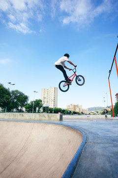 Young man doing jumps on his BMX bike in a skate park.