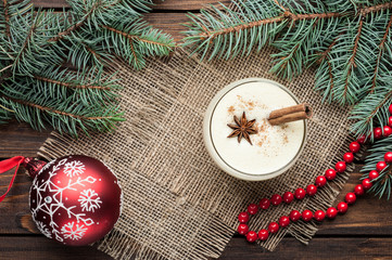 eggnog cocktail in glass arranged with christmas decoration on wooden table