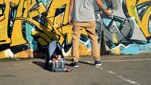 A graffiti artist prepares to use a yellow paint can. 