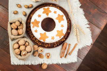 homemade traditional fruit cake on clay plate decorated with raisins and nuts at wooden table top view