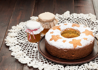homemade traditional fruit cake on clay plate decorated with honey jars at wooden table