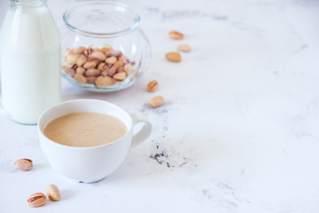 Coffee with milk and pistachios on wooden table, copy space