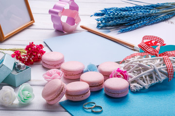 Pink heart shaped macaroons and wedding rings with postcard. place for inscription.