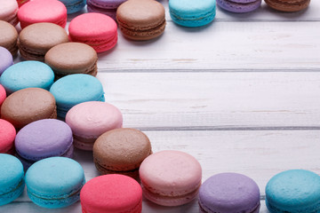 Assorted colorful french cookies macaroons on a white wooden background. Space for text.