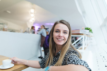 Portrait of a smiling business woman blond woman in a stylish light cafe for a cup of coffee. Coffee break in the restaurant.