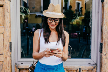 .Pretty young woman walking around downtown in a summer day using her mobile phone, talking and texting. Lifestyle portrait.